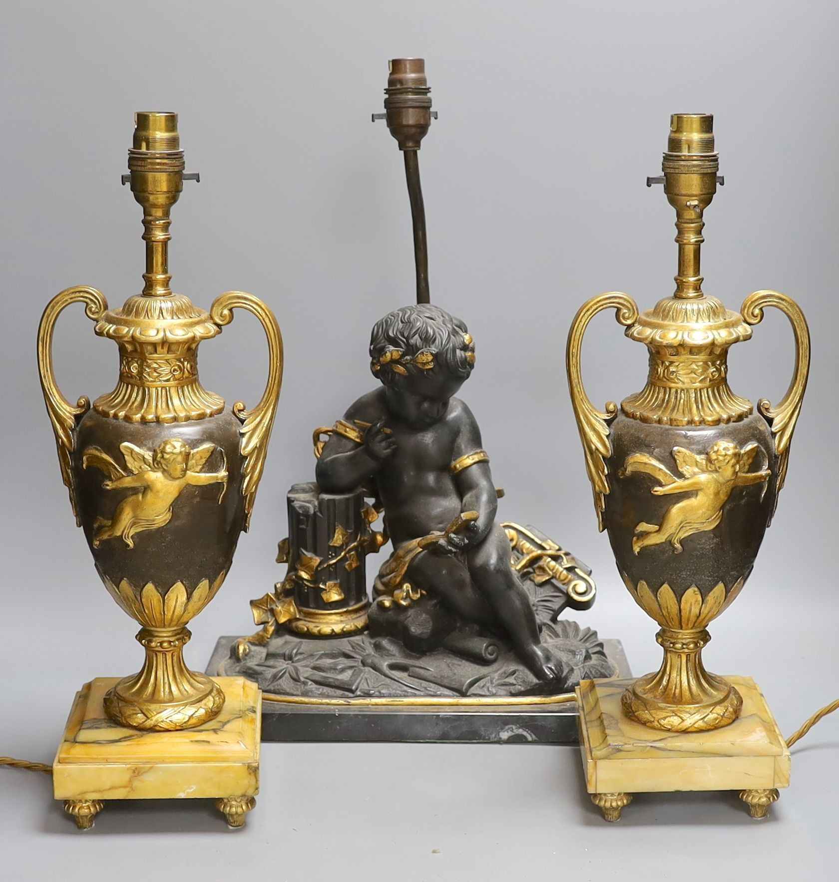 A pair of ornate guilt vase style lamps on marbled base, together with a seated cherub table lamp, 45cm tall, (3)